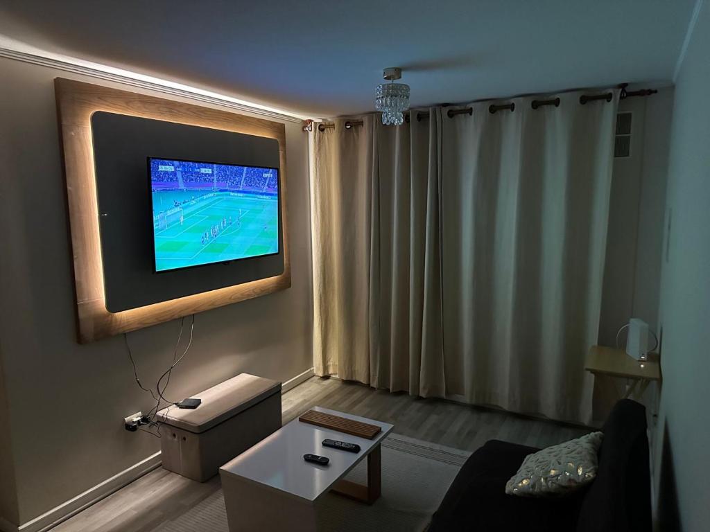 sala de estar con TV de pantalla plana en la pared en Alto mar II, en Viña del Mar