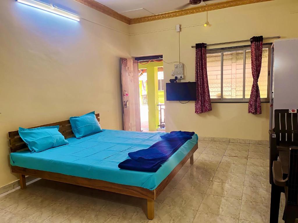 1 dormitorio con cama con sábanas azules y ventana en Coco Hut , Devbaug en Malvan