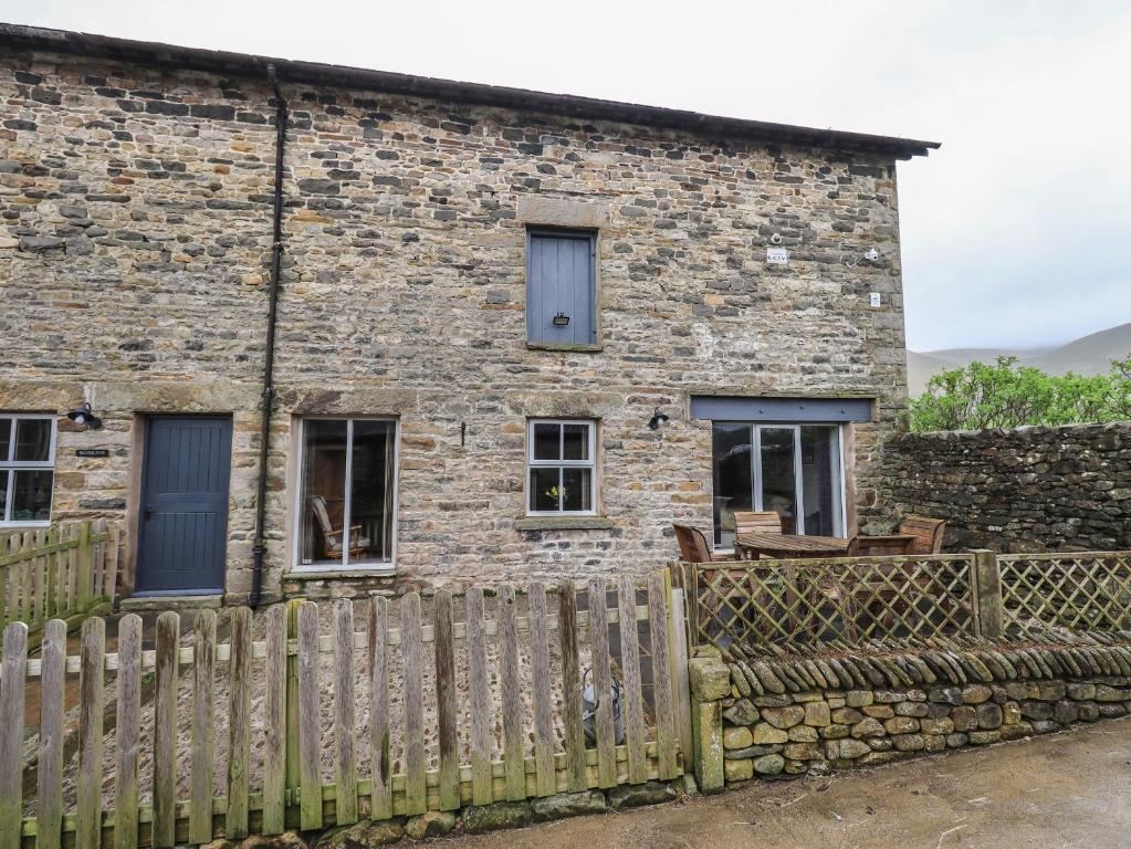 a stone house with a wooden fence in front of it at Boskins in Sedbergh