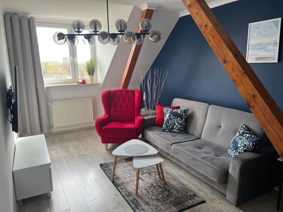 a living room with a couch and a red chair at Attic close to the beach and city center in Kołobrzeg