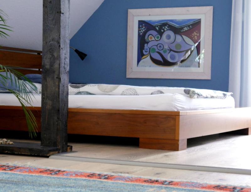 Ce lit en bois se trouve dans une chambre dotée d'un mur bleu. dans l'établissement ZwischenRaum, à Wuppertal