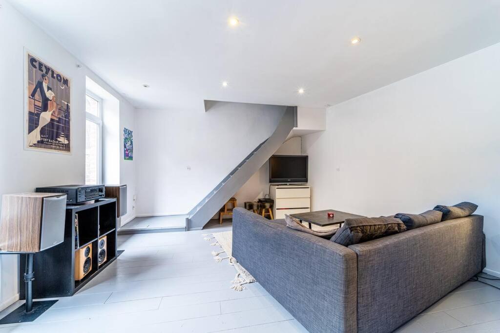 ein Wohnzimmer mit einem Sofa und einer Treppe in der Unterkunft Loft, proximité centre et gare in Lille