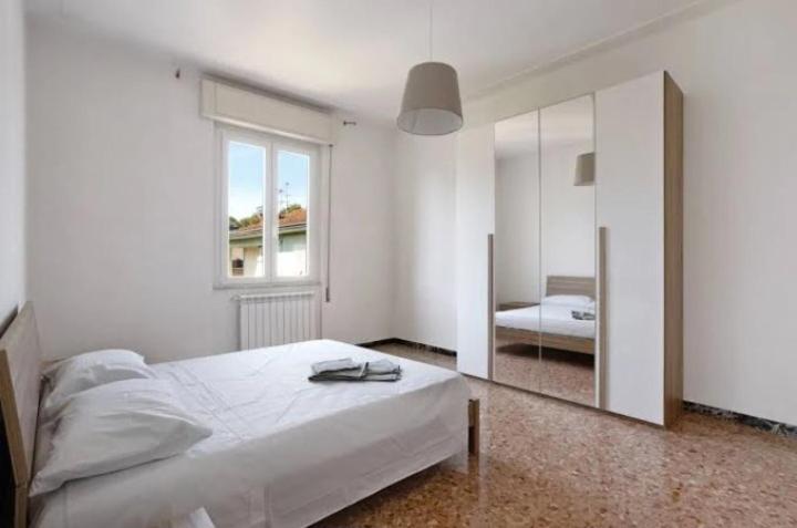 Habitación blanca con cama y espejo en Casa vacanze il Melograno en La Spezia