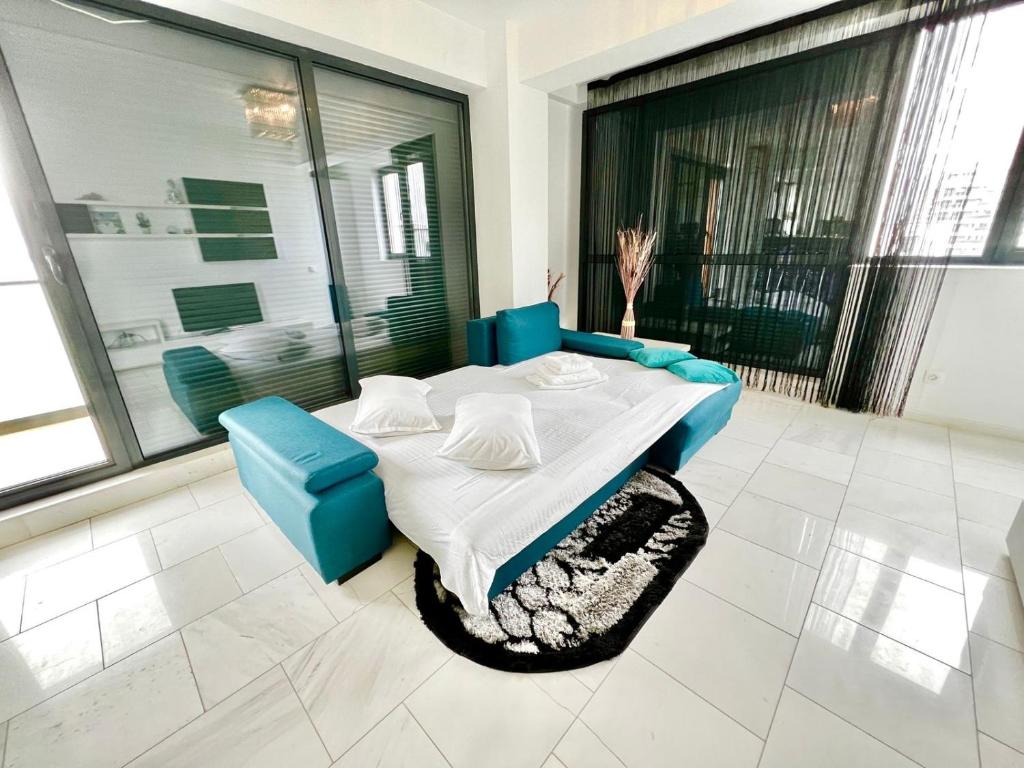 Una habitación con una mesa y un sofá azul y ventanas. en SOPHIA LAKE VIEW SUITE, en Mamaia