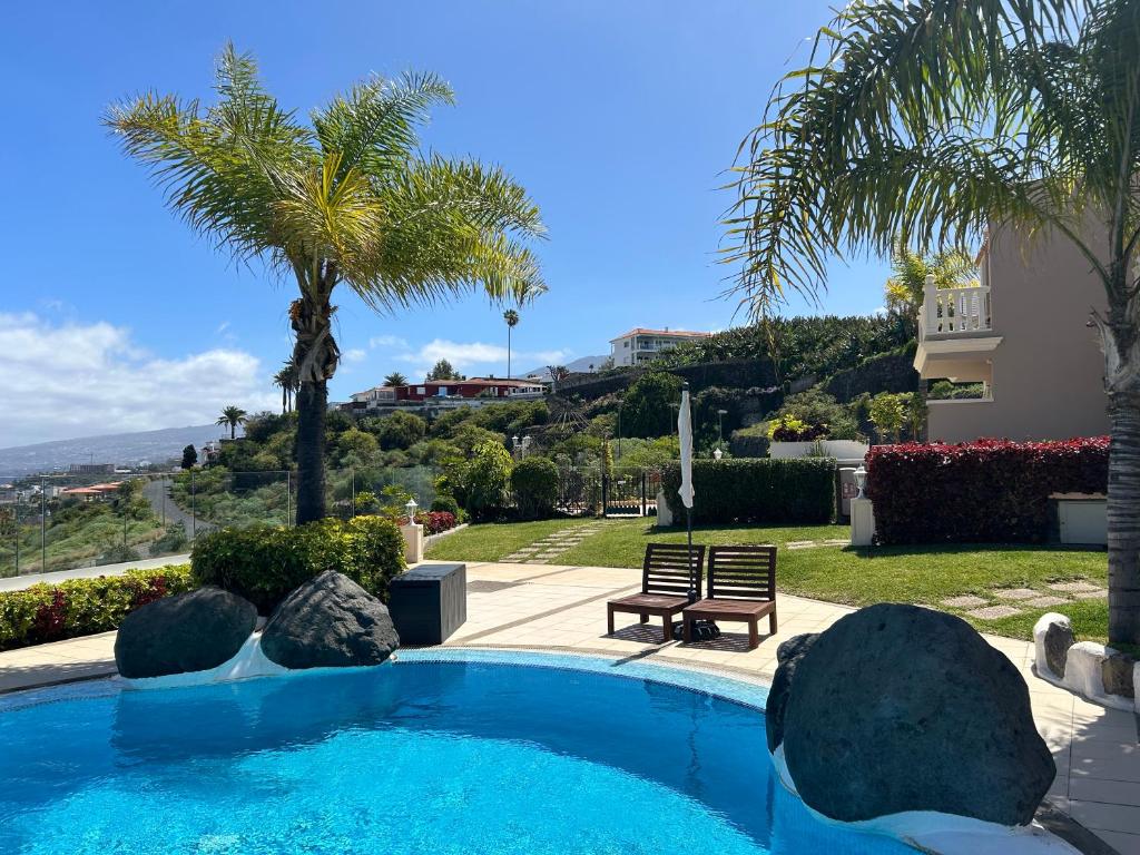 - une piscine avec un banc et des palmiers dans l'établissement Hermosa vista, à Puerto de la Cruz