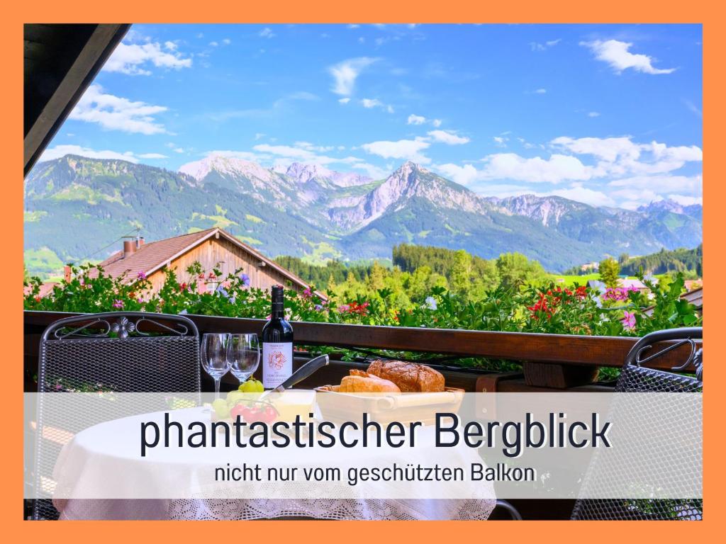 a table with a glass of wine and a view of mountains at Biohof Burger, 3 sonnige Fewo, alle mit Balkon, Spielzimmer, Grillhütte, 7 km vor Oberstdorf in Bolsterlang