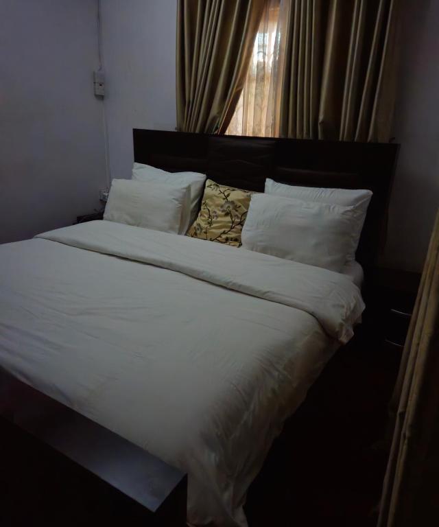 Quiet and comfortable home في لاغوس: سرير ذو أغطية ومخدات بيضاء ونافذة