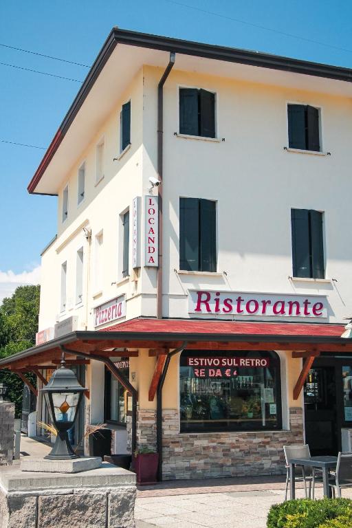 ein weißes Gebäude mit einem Restaurant davor in der Unterkunft Locanda Munerato in Padua
