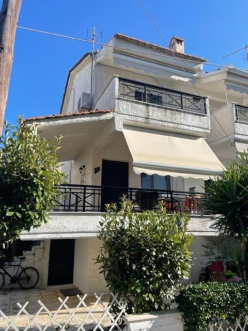 a white house with a balcony with a dog on top at Lefki's House in Agiokampos