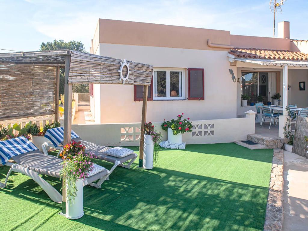 a backyard with a green lawn and a house at Casa Rosella - Formentera Break in San Ferrán de ses Roques