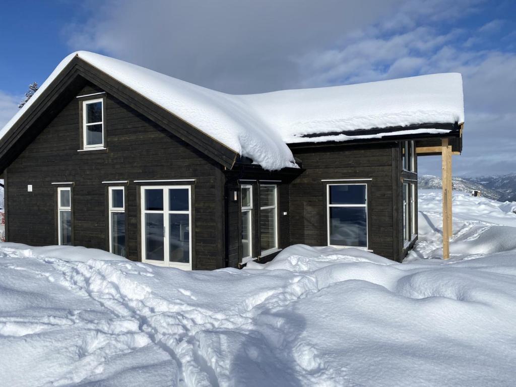 ein schneebedecktes Haus mit einem Schneehaufen in der Unterkunft Nydelig hytte ved Voss Ski og Tursenter in Giljane