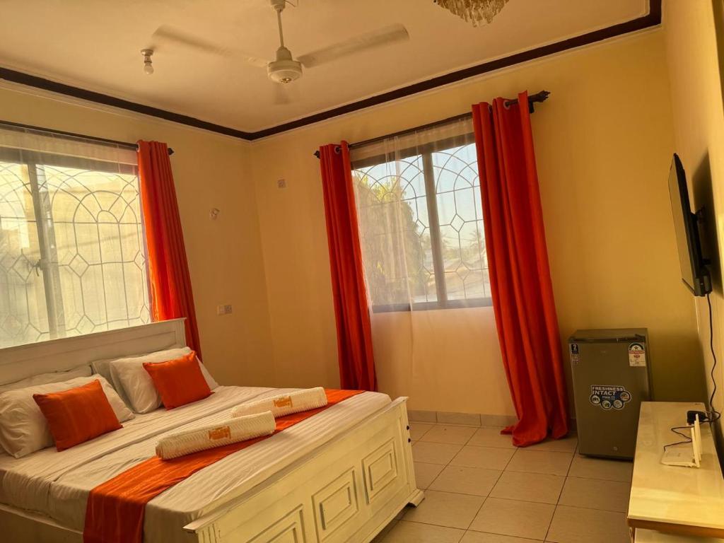 a bedroom with two beds and red curtains at Cherry home in Mombasa