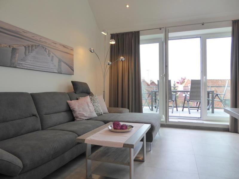 uma sala de estar com um sofá cinzento e uma mesa em Premium-Penthouse Oceans Eleven, Am Alten Deich 14 11 em Dangast