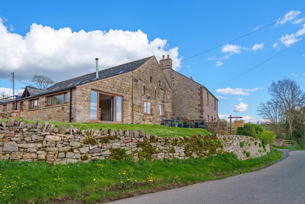 a stone house on a hill with a stone wall at 1 Peggies Barn - Rural cottage with great views in Maulds Meaburn