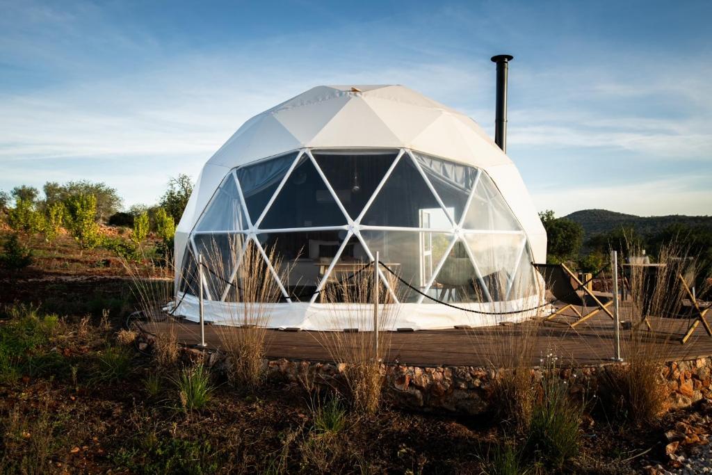 een glazen iglo zit in een veld bij Glamping Casa Esteval in Rocha Amarela
