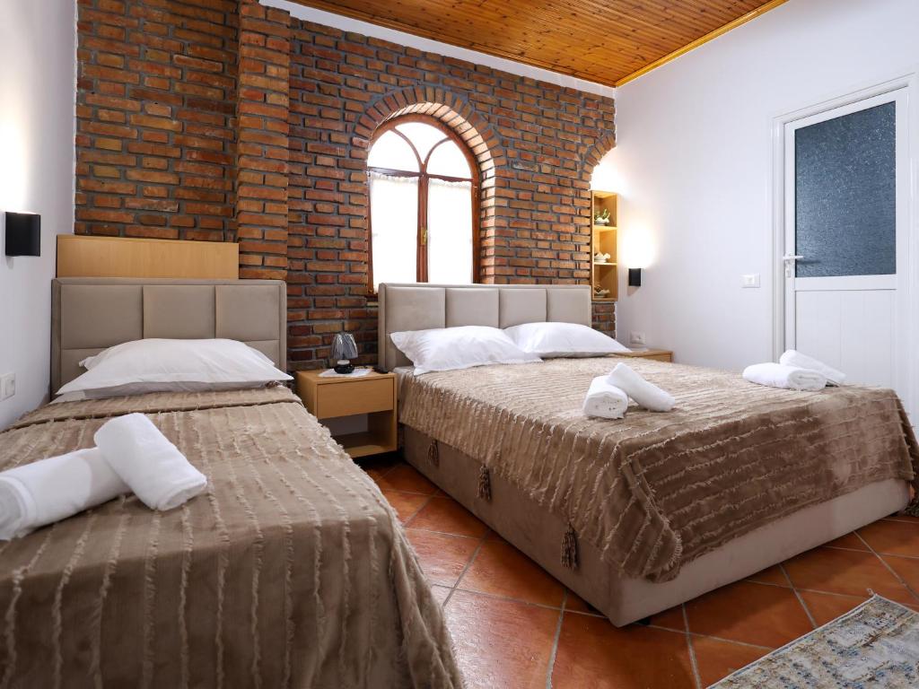 two beds in a room with a brick wall at Hotel Boutique BUZI in Berat