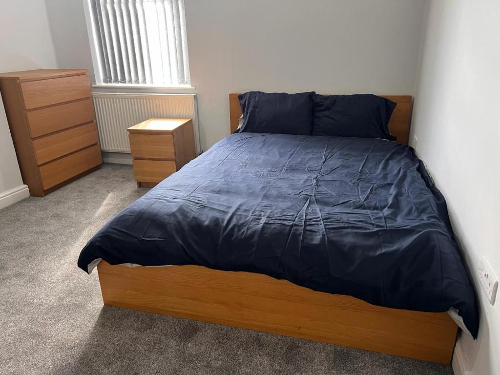 a bedroom with a bed with a blue comforter at Nice 2Bedroom house for Family in Nottingham