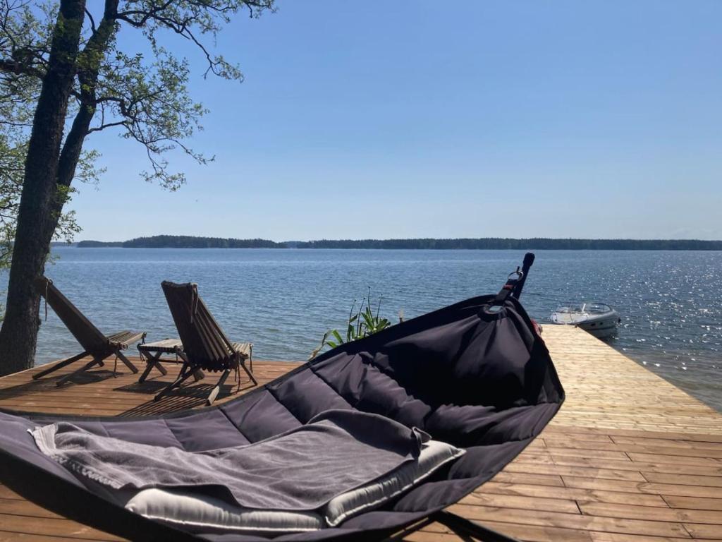 a hammock and two chairs on a dock near the water at Stay North - Villa Kalksved in Sipoo