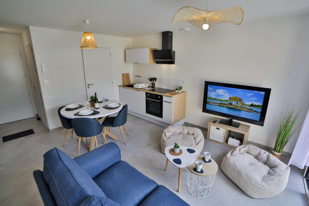 ein Wohnzimmer mit einem blauen Sofa und einem TV in der Unterkunft BZHouse - Terrasse - Climatisation - Wifi in Belz