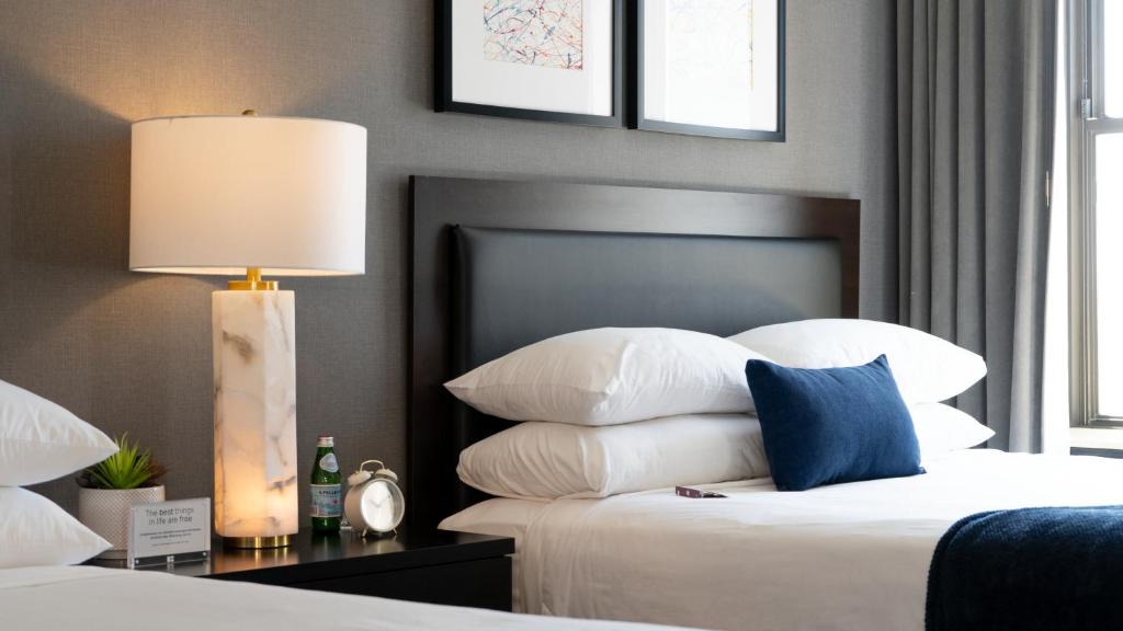 a bedroom with a bed with a lamp and pillows at Roomza Inner Harbor at Lord Baltimore in Baltimore