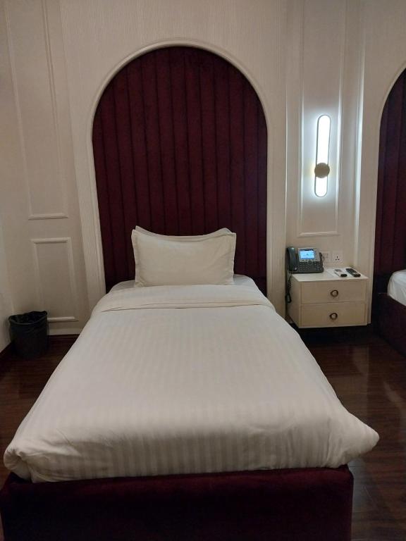 a bedroom with a large white bed with a red headboard at Hotel MERIDIAN in Kary