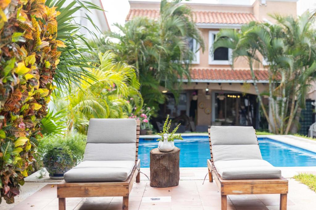 a pair of lounge chairs next to a swimming pool at Magnifica Villa Palmeras Pok ta Pok Zona Hotelera Cancun in Cancún