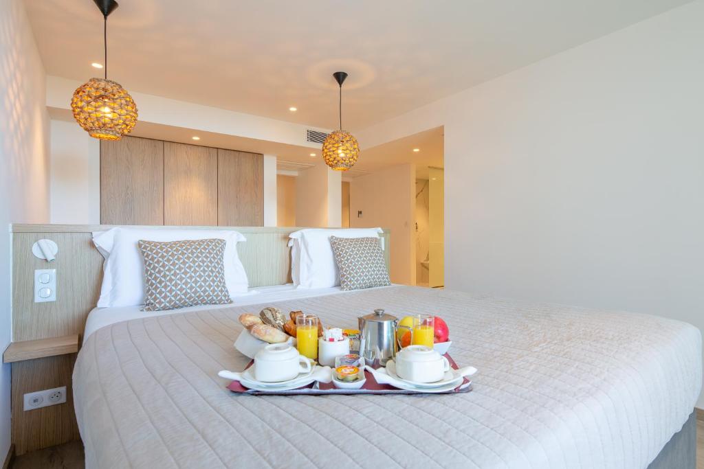 a breakfast tray on a bed in a bedroom at Hôtel La Plage in Sainte-Maxime