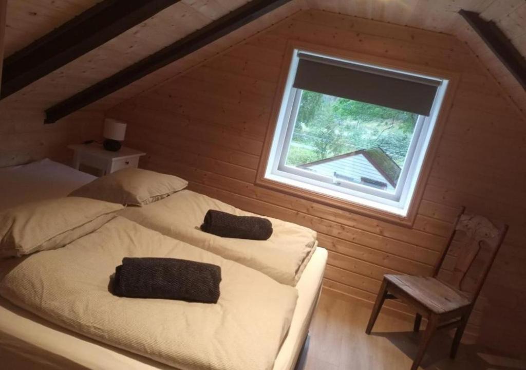 een slaapkamer met een bed met een raam en een stoel bij An authentic experience in picturesque Eidfjord in Eidfjord