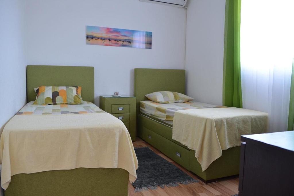 two beds in a room with green and white at Milica Apartments in Sutomore