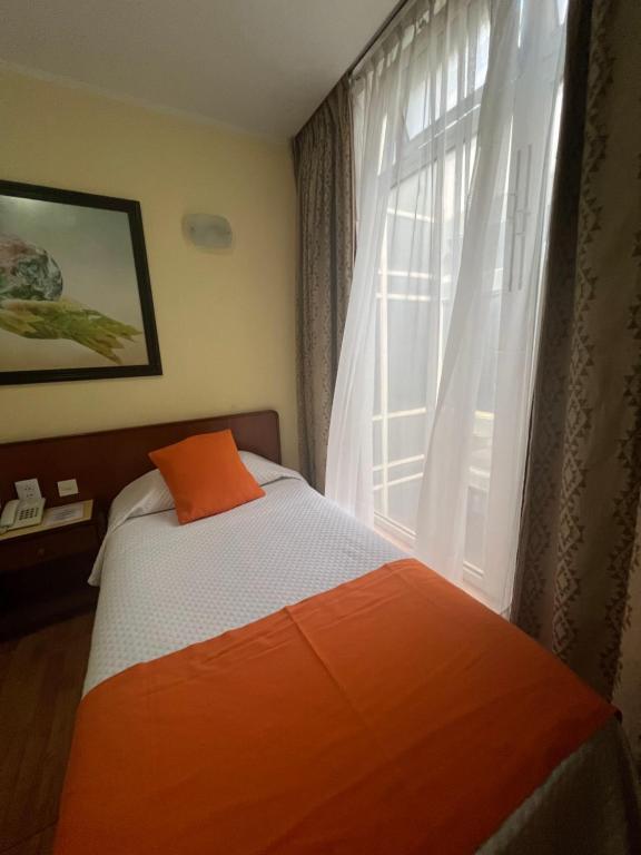 a bed with an orange pillow next to a window at Atlantida Hotel in Río Grande