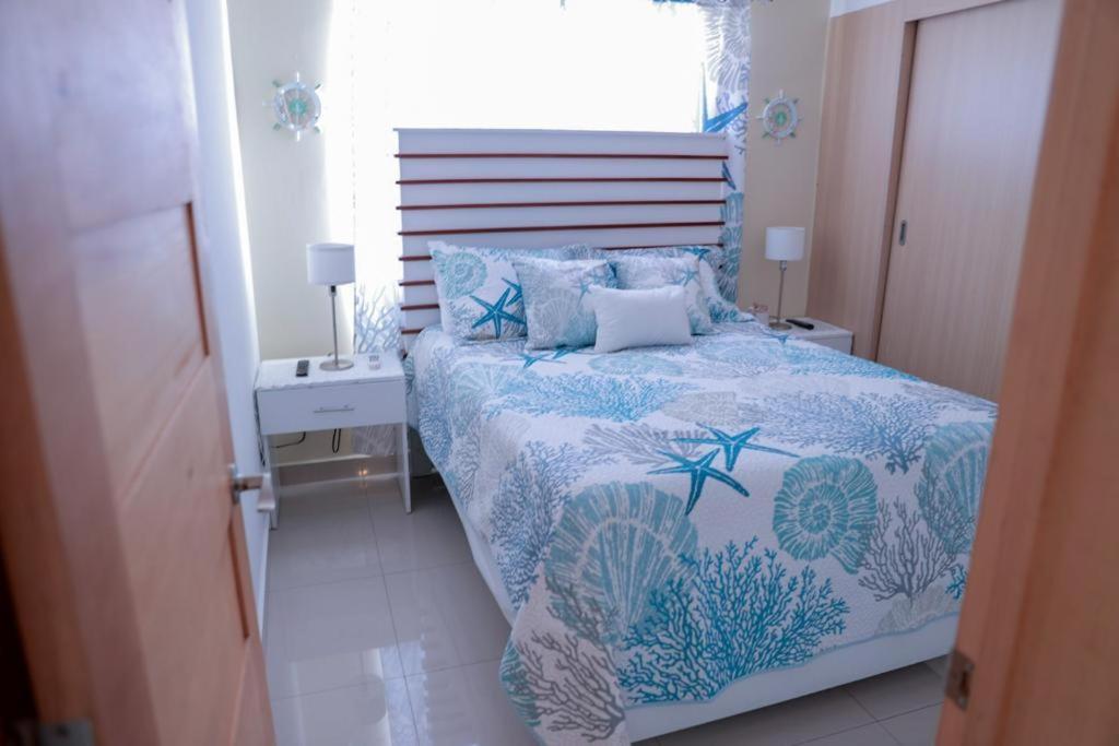 1 dormitorio con 1 cama con edredón azul y ventana en BOCA DEL MAR APTO, en Cuevas