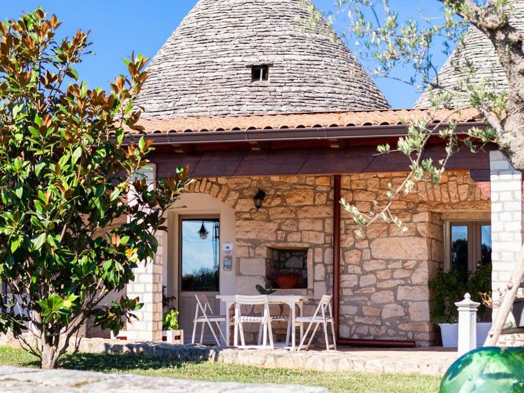 a small stone house with a table and chairs at Masseria trulli pietra antica in Noci