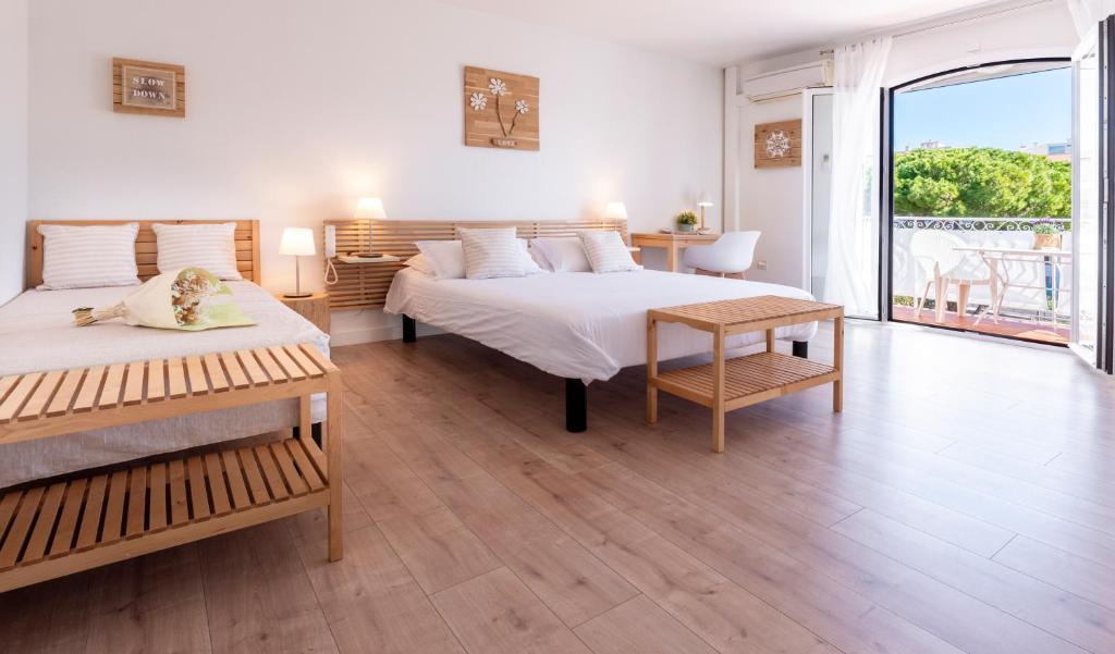 a bedroom with two beds and a large window at Hôtel & Studios Astor in Juan-les-Pins