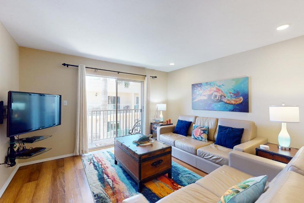 a living room with a couch and a flat screen tv at The Palm Bay Club Unit 311 in Siesta Key