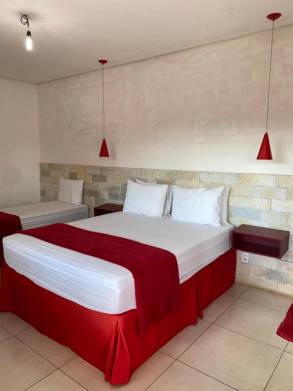 um quarto com 2 camas com lençóis vermelhos e brancos em Pousada Aliany Lôbo em Pirenópolis