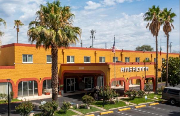 a large yellow building with palm trees in front of it at Hotel Americana in Nogales