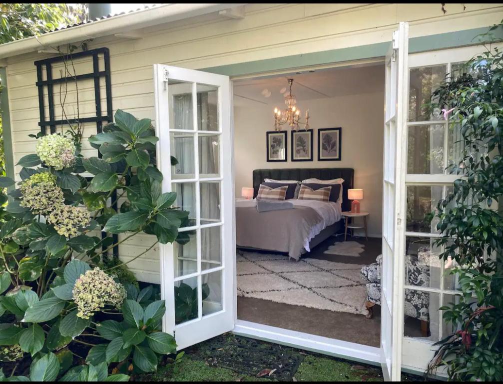 a bedroom with a bed and a door leading to a room at Green Door Cottage in Greytown