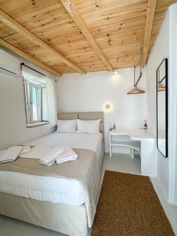 a white bedroom with a bed and a desk at Lythi Kythnos in Kithnos