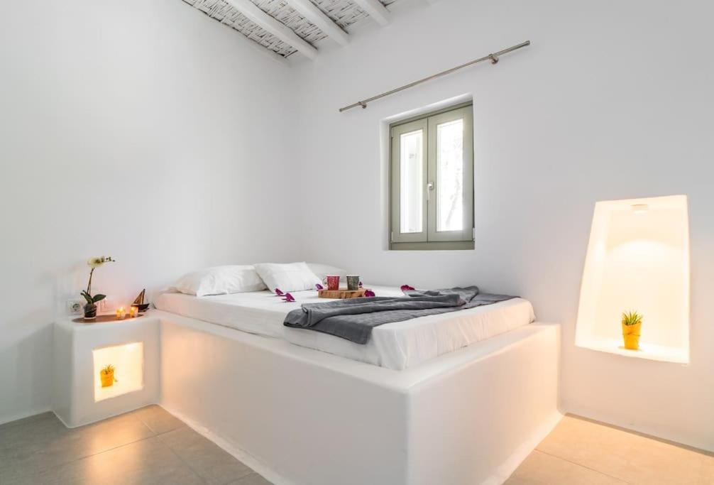 a white room with a bed with a window at Armonia Guesthouse close to Mykonos town in Dexamenes
