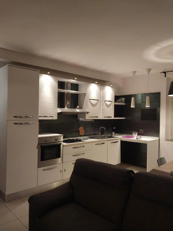 a kitchen with white cabinets and a couch in a room at Casa Galileo in Reggio di Calabria
