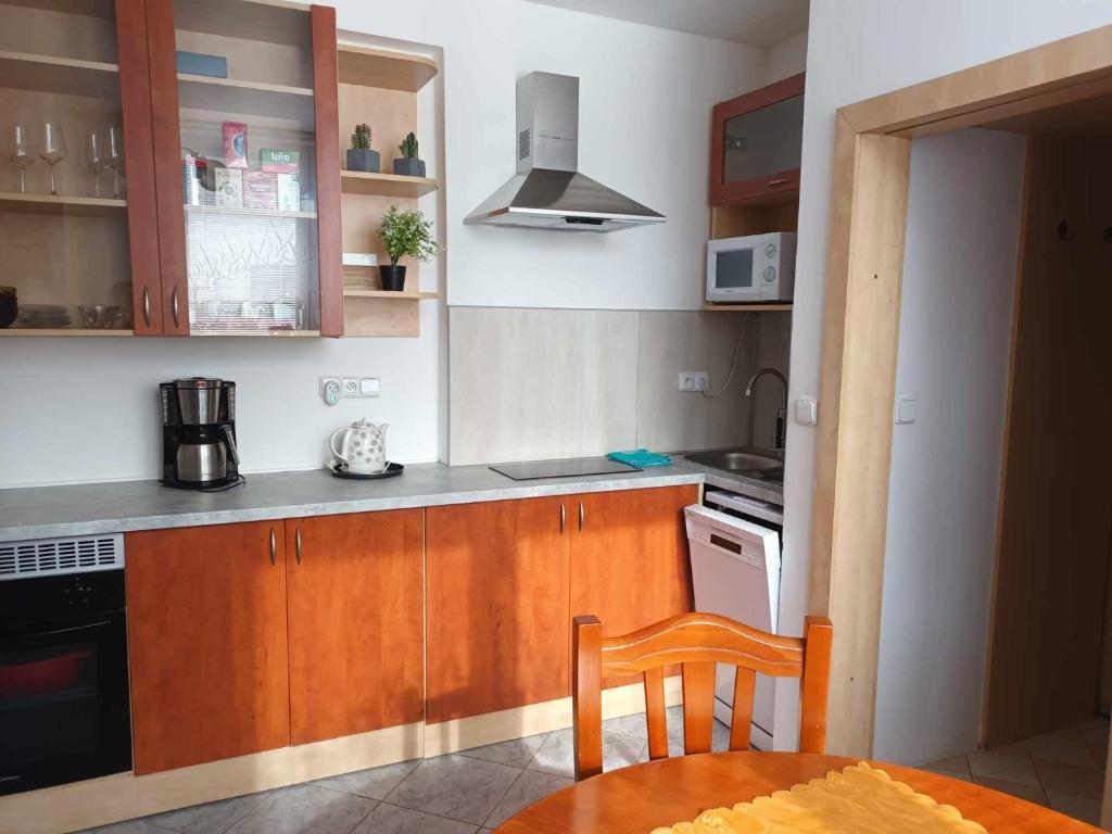 - une cuisine avec des placards en bois, une table et une cuisinière dans l'établissement APARTMAN OLOMOUC 2KK, à Olomouc