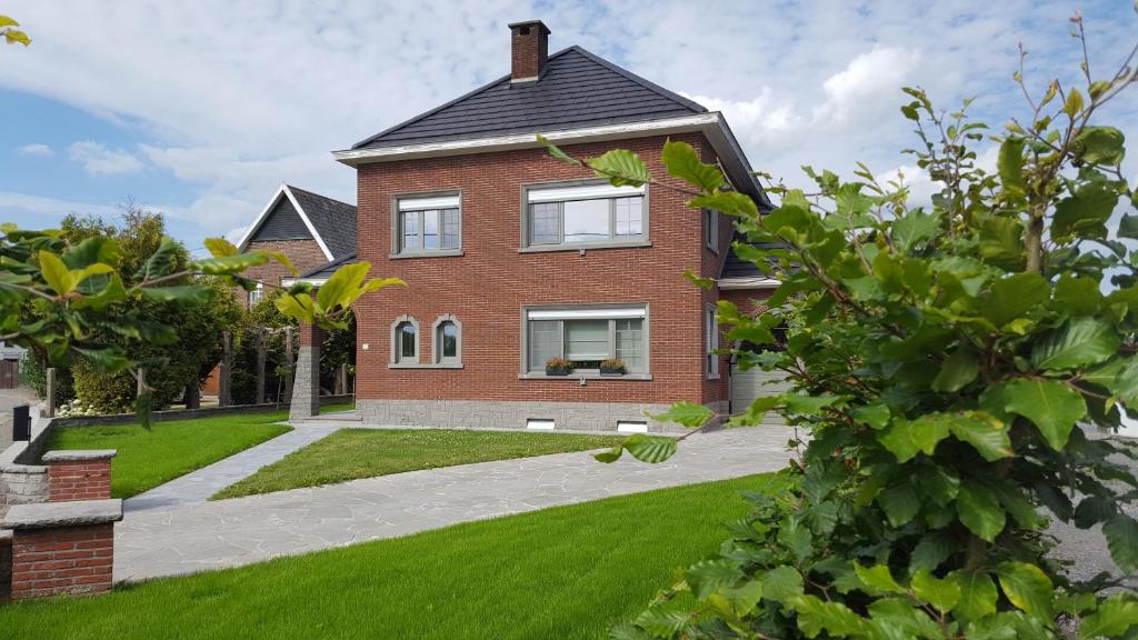 uma casa de tijolos com um relvado verde em B&B Krieken de Jour em Ninove