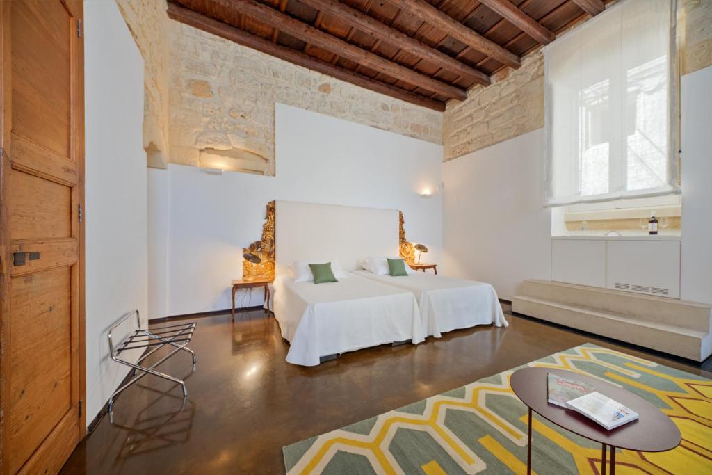 - une chambre avec un lit dans une pièce avec une table dans l'établissement Palazzo Personè Dimora Storica, à Lecce