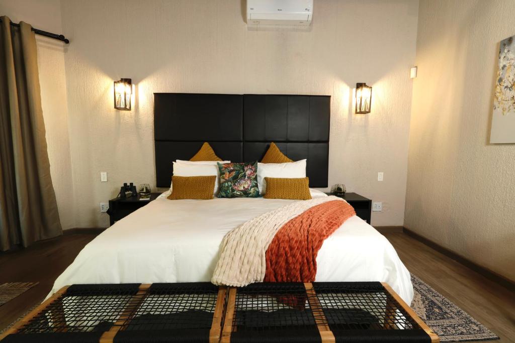 1 dormitorio con 1 cama grande y cabecero grande en Shingalana Guest House en Hazyview