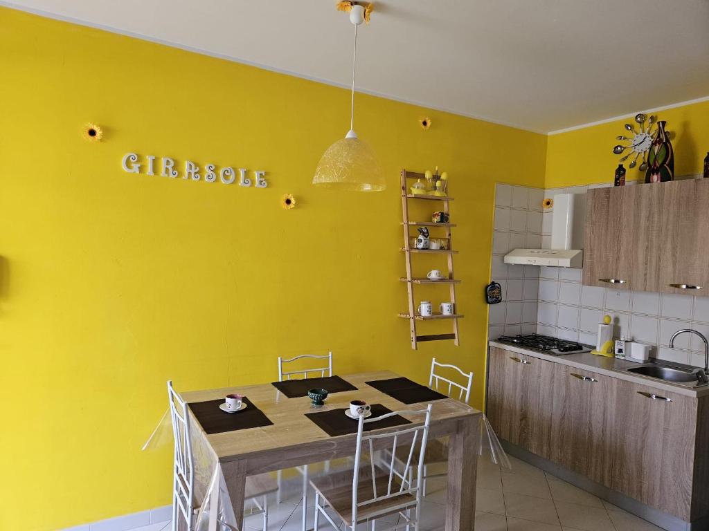 a kitchen with a table and a yellow wall at Appartamento Girasole in San Vito lo Capo