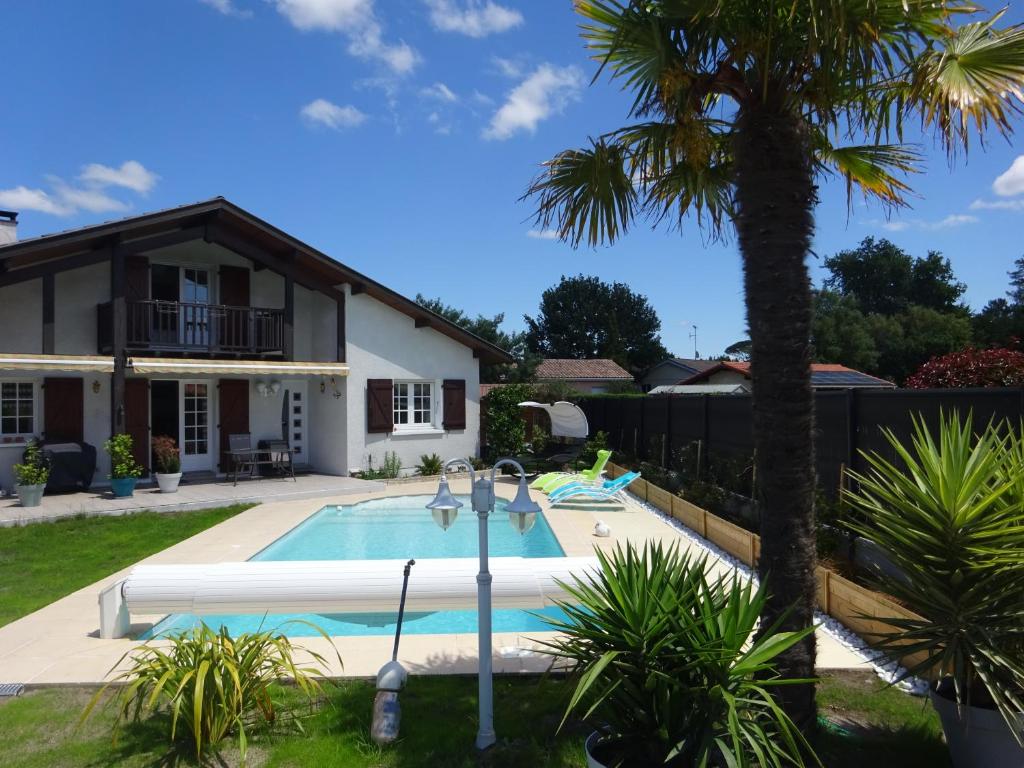 une maison avec une piscine et un palmier dans l'établissement Landaise idéale pour 1 à 2 couples avec enfants, à Azur