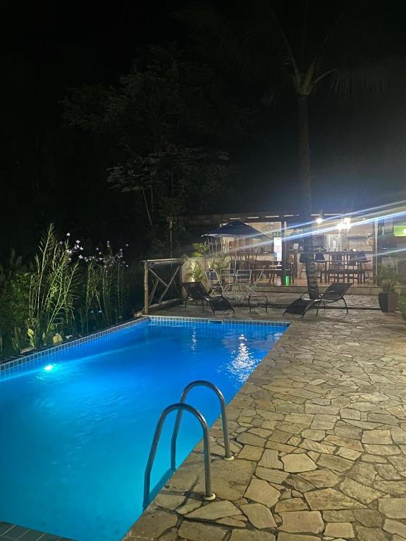 a blue swimming pool at night with chairs around it at Pousada céu azul Paraty in Paraty
