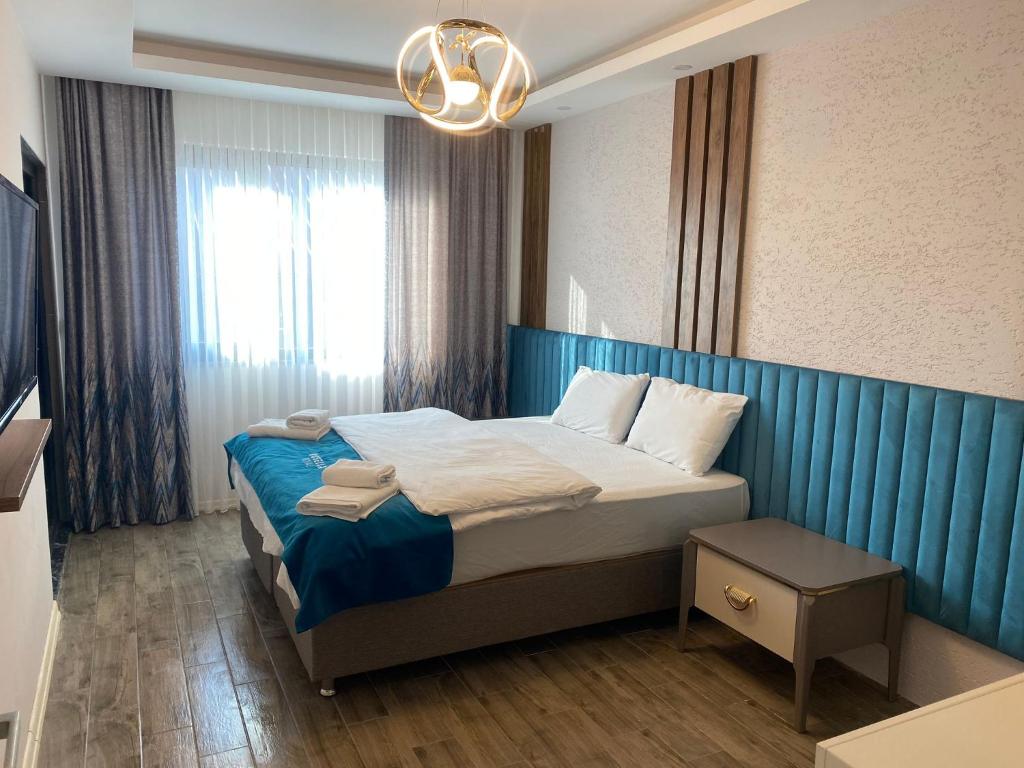 1 dormitorio con 1 cama grande y cabecero azul en Rosella Royal Suit - روزيلا رويال, en Trabzon