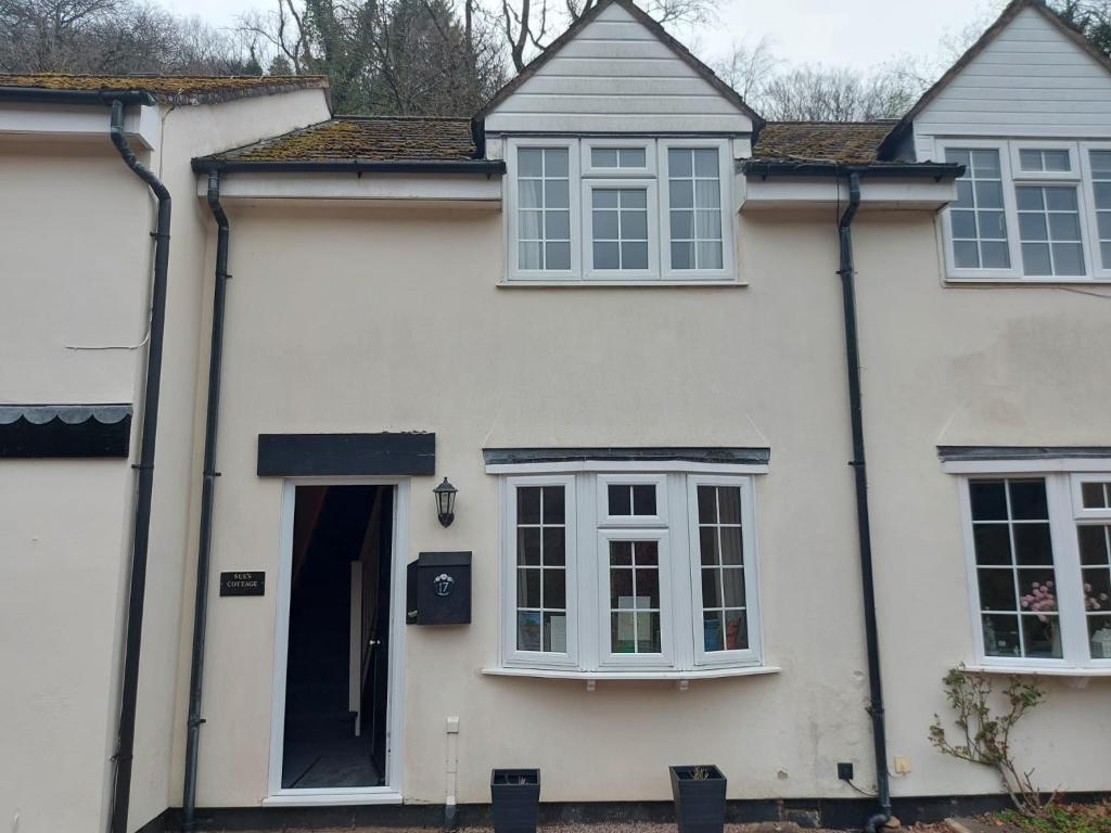 a white house with white windows and a door at Sue's Cottage. in Symonds Yat