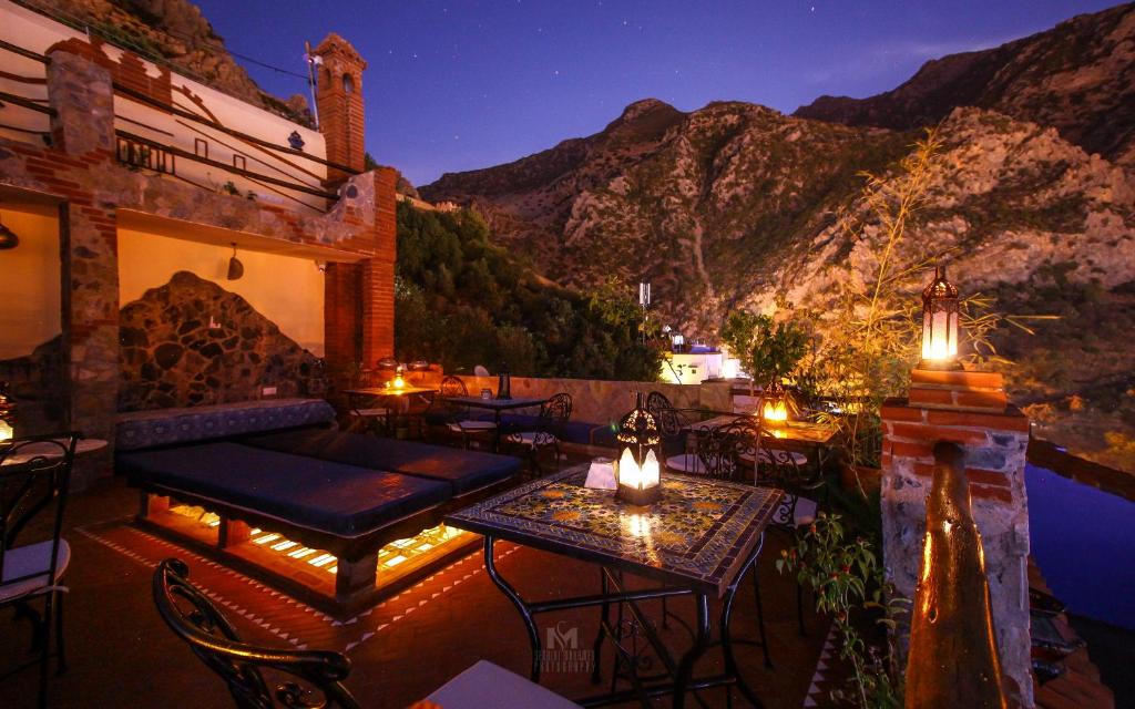 - une terrasse avec des tables et des chaises la nuit avec des montagnes dans l'établissement Riad Bab Mahruk, à Chefchaouen